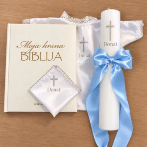 Personalizirani krsni set sa srebrnim motivima koji sadrži Bibliju, krsnu svijećusa plavnom mašnom, krsnu maramicu i krsnu košuljicu bijele boje